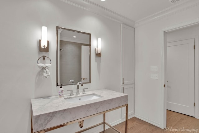 bathroom featuring sink, ornamental molding, and hardwood / wood-style floors