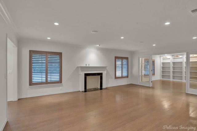 unfurnished living room featuring ornamental molding, light wood-type flooring, and a high end fireplace