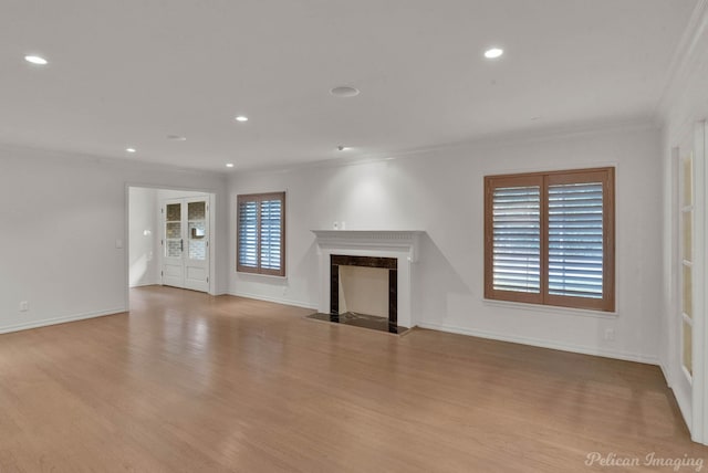 unfurnished living room featuring ornamental molding, a premium fireplace, and light wood-type flooring