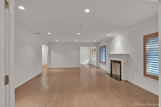 unfurnished living room with ornamental molding, a fireplace, and light hardwood / wood-style flooring