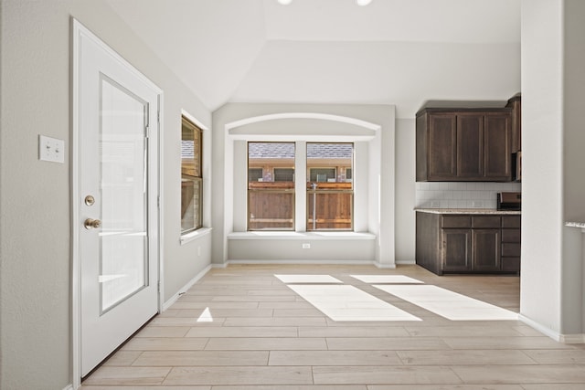 unfurnished dining area with lofted ceiling and light hardwood / wood-style floors