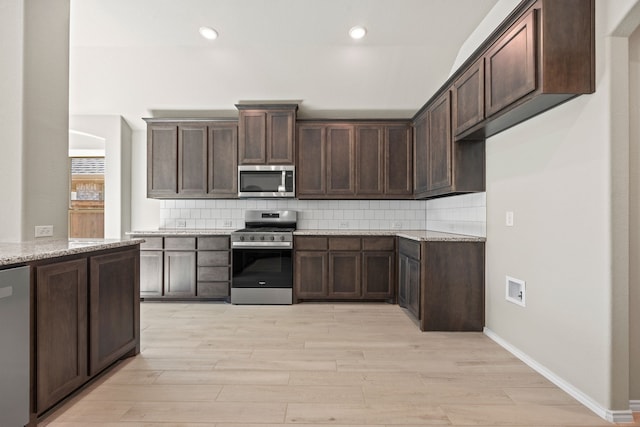 kitchen with light stone counters, stainless steel appliances, and dark brown cabinetry