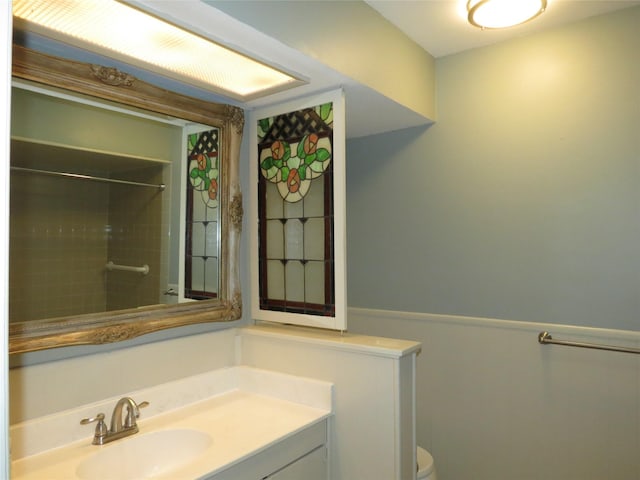 bathroom featuring tiled shower, vanity, and toilet