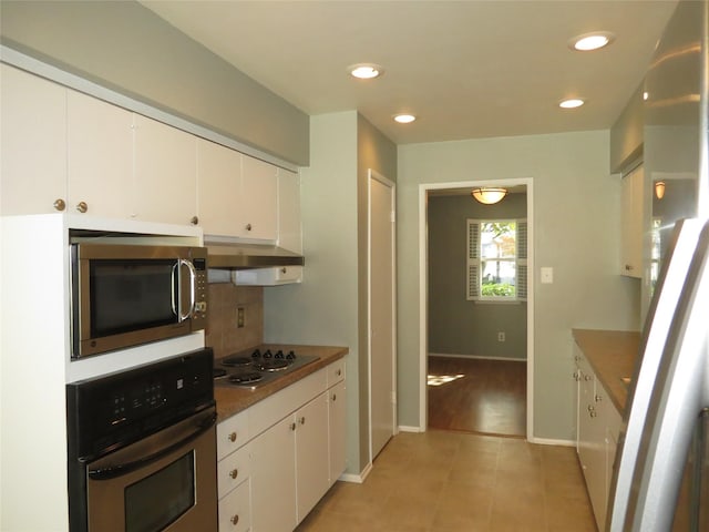 kitchen featuring light tile patterned floors, decorative backsplash, stainless steel appliances, and white cabinets