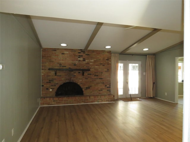 unfurnished living room with lofted ceiling with beams, hardwood / wood-style floors, a fireplace, and french doors