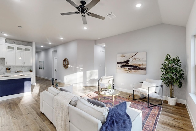 living room featuring vaulted ceiling, ceiling fan, and light wood-type flooring