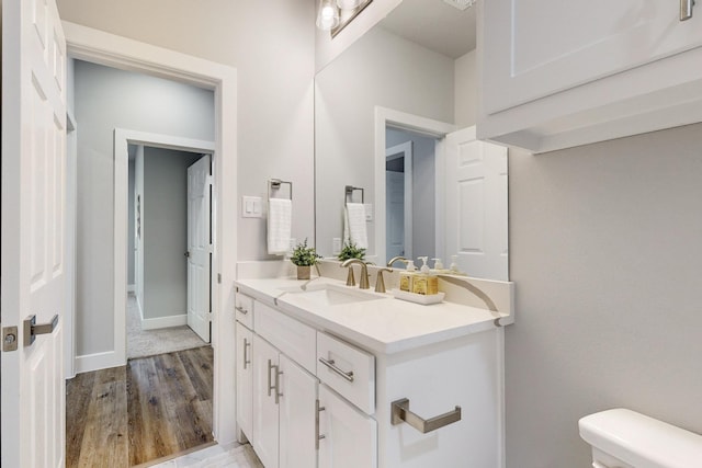 bathroom with hardwood / wood-style flooring, vanity, and toilet