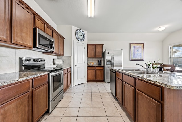 kitchen with sink, light tile patterned floors, a kitchen island with sink, stainless steel appliances, and tasteful backsplash