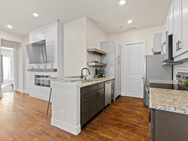 kitchen featuring light stone counters, a breakfast bar, visible vents, appliances with stainless steel finishes, and open shelves