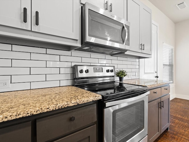 kitchen featuring white cabinets, visible vents, stainless steel appliances, and light stone counters