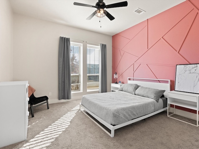 bedroom with light carpet, ceiling fan, visible vents, and an accent wall