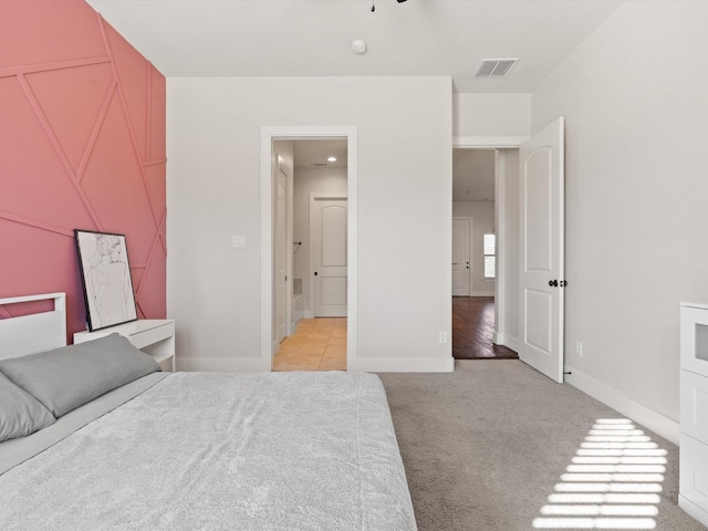 bedroom featuring baseboards, visible vents, and light colored carpet