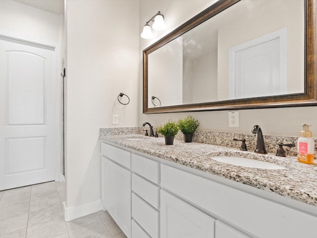 bathroom featuring baseboards, double vanity, a sink, and tile patterned floors