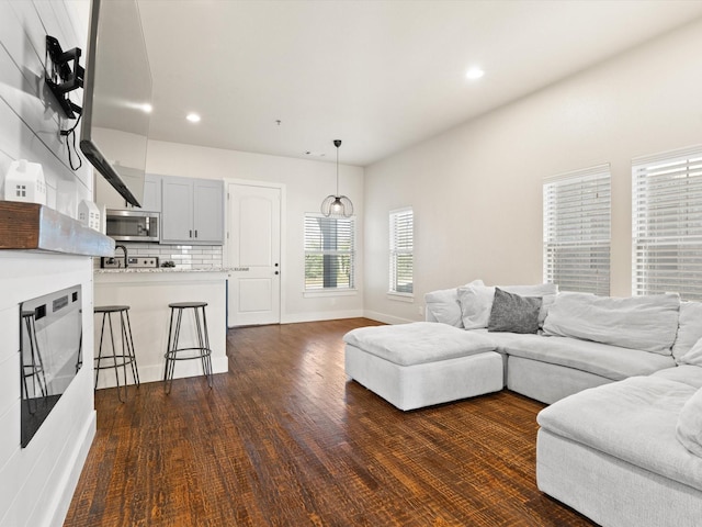 living room with dark wood-type flooring, recessed lighting, and baseboards