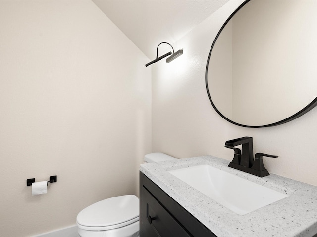 half bath with toilet, vaulted ceiling, and vanity