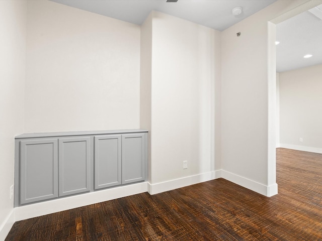 spare room with baseboards and wood finished floors