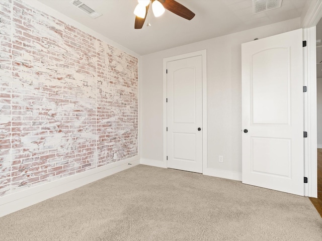 unfurnished bedroom featuring brick wall, carpet, visible vents, and baseboards