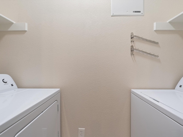 laundry room featuring laundry area, a textured wall, and separate washer and dryer