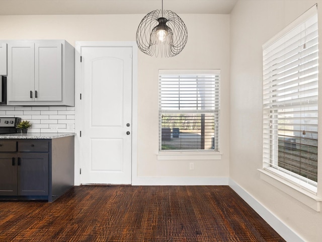 unfurnished dining area featuring baseboards and dark wood finished floors