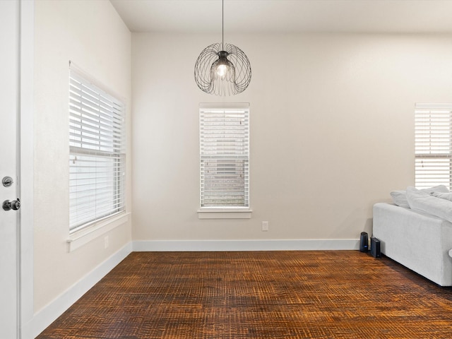 unfurnished room with baseboards and dark colored carpet