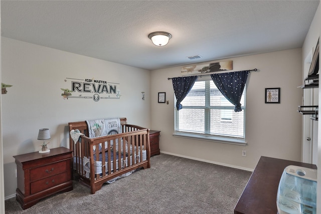 carpeted bedroom with a crib and a textured ceiling