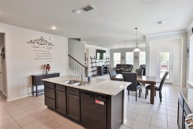 kitchen with light tile patterned floors, hanging light fixtures, black dishwasher, light stone countertops, and a center island with sink