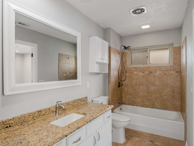 full bathroom featuring tiled shower / bath combo, vanity, a textured ceiling, tile patterned floors, and toilet