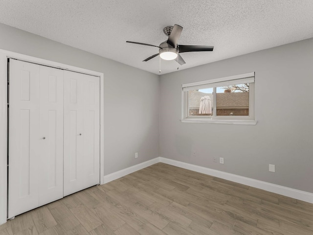 unfurnished bedroom with ceiling fan, light hardwood / wood-style floors, a closet, and a textured ceiling