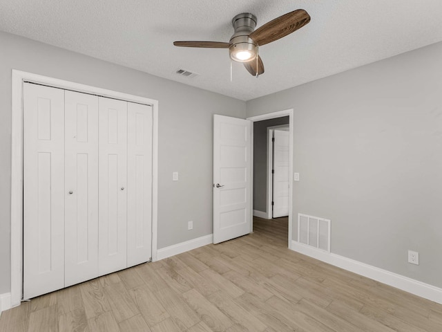 unfurnished bedroom with ceiling fan, light hardwood / wood-style floors, a closet, and a textured ceiling