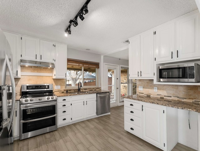 kitchen featuring dark stone countertops, white cabinetry, and appliances with stainless steel finishes