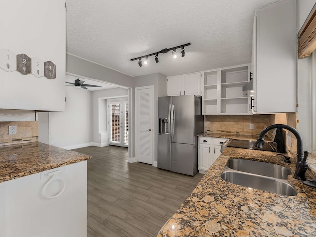 kitchen featuring stainless steel refrigerator with ice dispenser, sink, dark stone countertops, and white cabinets