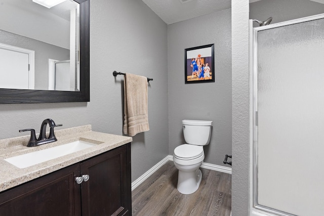 bathroom with an enclosed shower, wood-type flooring, vanity, and toilet