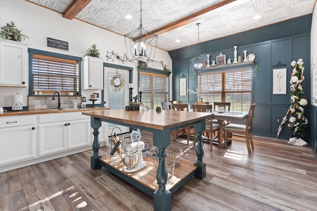 kitchen with sink, light hardwood / wood-style flooring, butcher block counters, white cabinetry, and decorative light fixtures