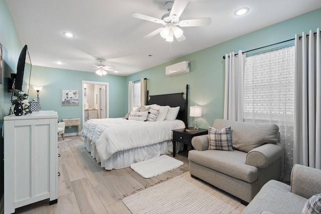 bedroom with ceiling fan, ensuite bath, light hardwood / wood-style floors, and a wall mounted AC