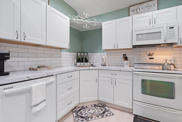 kitchen featuring sink, white appliances, white cabinetry, light stone countertops, and decorative backsplash