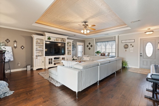 living room with a raised ceiling, crown molding, and dark wood-type flooring