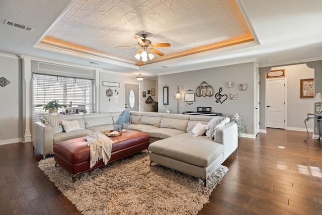 living room with dark hardwood / wood-style flooring, ornamental molding, and a raised ceiling