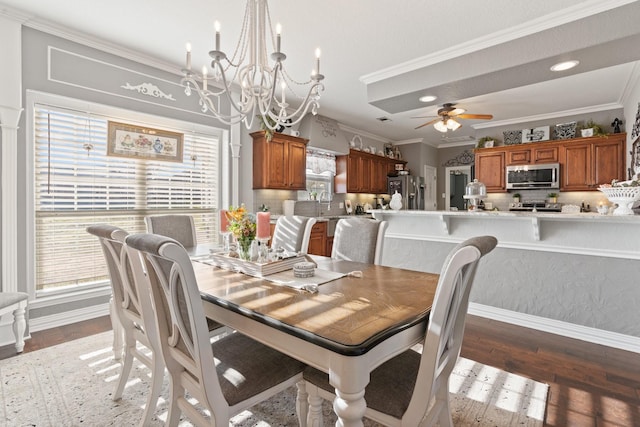 dining space with crown molding, sink, dark wood-type flooring, and ceiling fan with notable chandelier