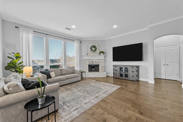 living area featuring baseboards, arched walkways, wood finished floors, and ornamental molding