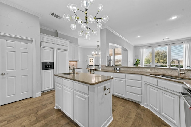 kitchen with visible vents, stainless steel dishwasher, white cabinetry, a sink, and wood finished floors