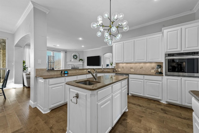 kitchen with arched walkways, oven, dark wood-type flooring, a sink, and decorative backsplash