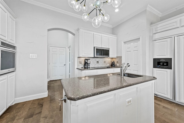 kitchen featuring arched walkways, appliances with stainless steel finishes, a sink, and crown molding