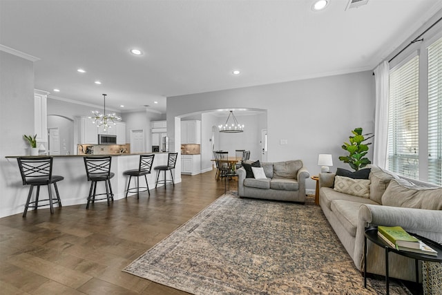 living area with a chandelier, arched walkways, and ornamental molding