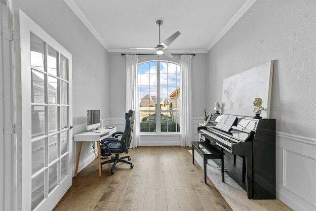 office featuring a wainscoted wall, crown molding, a ceiling fan, and wood finished floors