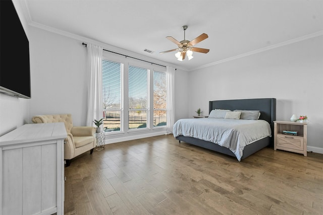 bedroom featuring baseboards, visible vents, ceiling fan, wood finished floors, and crown molding