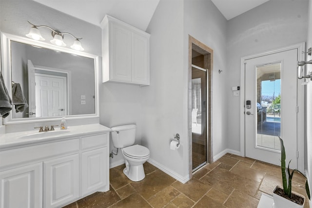 bathroom with stone tile flooring, toilet, a stall shower, vanity, and baseboards