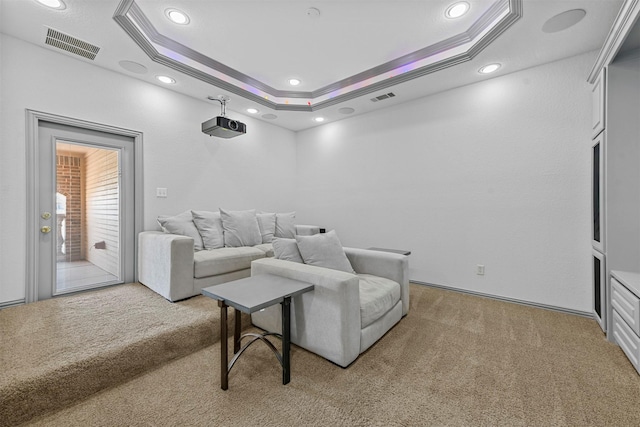 home theater featuring ornamental molding, a raised ceiling, visible vents, and light carpet