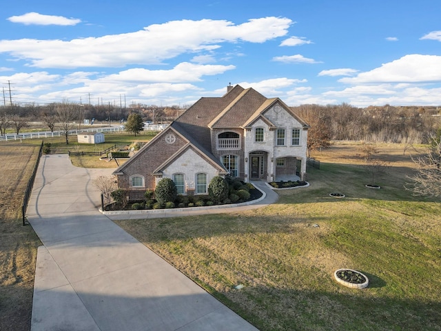 french provincial home with stone siding, fence, and a front lawn