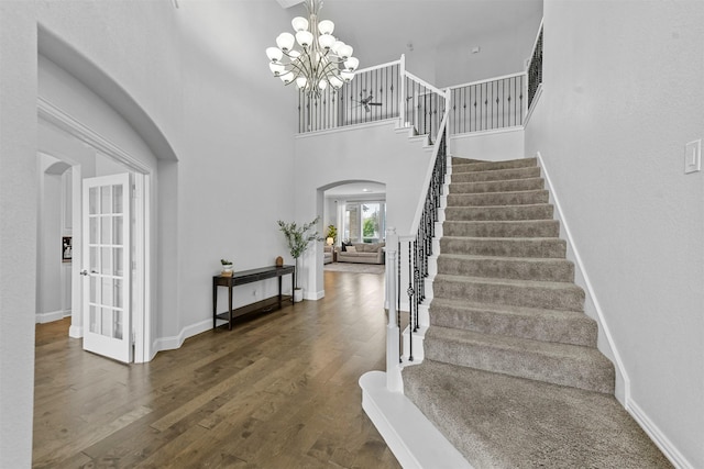 entrance foyer featuring arched walkways, french doors, stairway, and wood finished floors