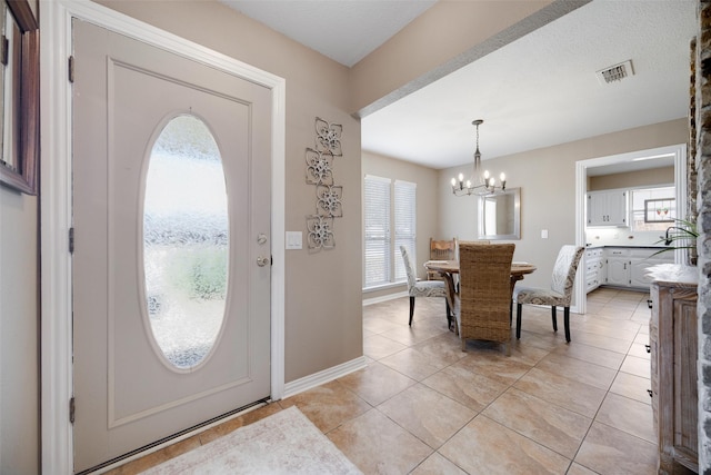 foyer entrance with plenty of natural light, light tile patterned floors, and a chandelier